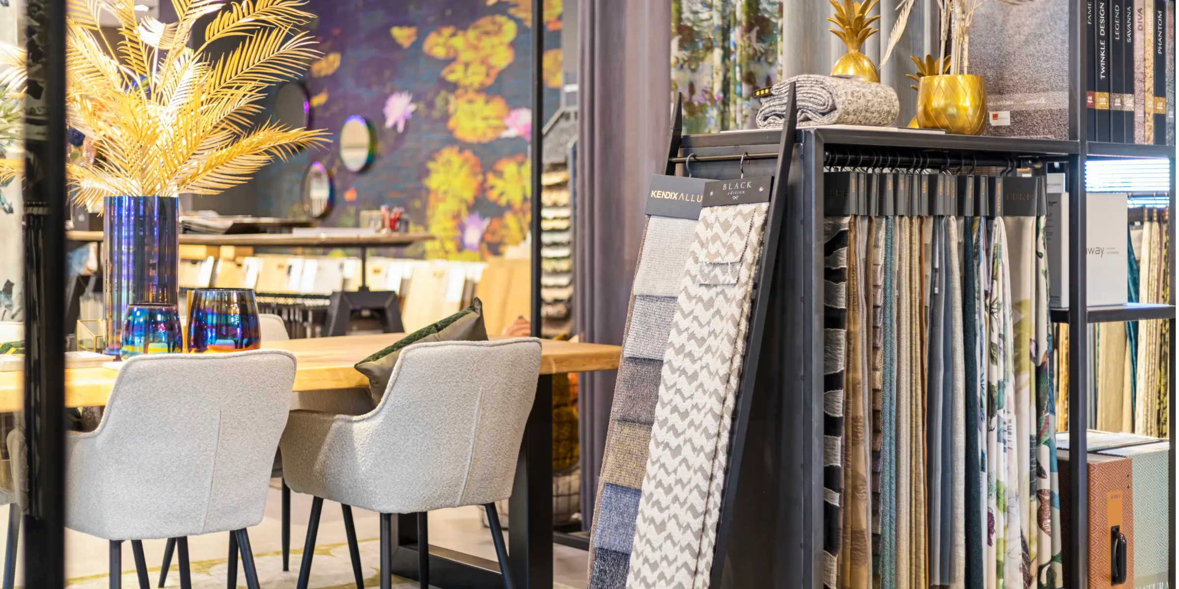 Cozy showroom with a wooden table, grey chairs, colourful decorations and a rack of fabric samples – scent marketing in a showroom enhances the atmosphere.